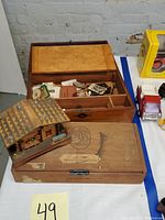 Overview of the three wooden boxes on a white surface, including the Swiss cottage music box, cigar box, and keepsake box with vintage paper items inside.