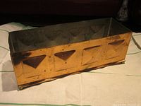 Image showing front and side view of rectangular copper planter with raised triangle designs and ball feet.