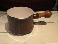 Brown Dansk Kobenstyle butter warmer saucepan with teak handle, showing inside and outer rim with minor enamel chips.