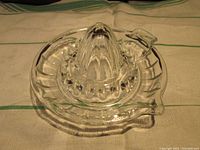 Top angle view of clear glass juicer showing circular spike arrangement around central cone and integrated handle and spout