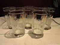 Set of 5 mid-century glasses with gold spade pattern and white vertical stripes on a table