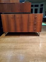 Front view showing two doors and three drawers on metal hairpin legs