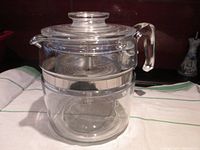Front view of entire assembled glass percolator showing the clear glass body, handle, lid, and metal band.