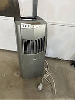 Front and side view of Amcor portable air conditioner showing vent grille and power cord.