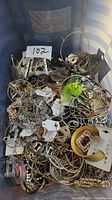 Top view of a plastic bin filled with assorted costume jewelry including bracelets, earrings, necklaces, and brooches in gold and silver tones.