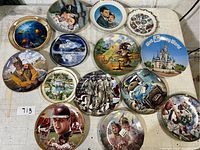 Overview of 14 assorted decorative and collector plates on table showcasing designs and themes