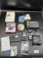 Photo shows a Roku 2 streaming player in box, Sony home phone with clock, spindle of CDs, HP 21 ink cartridge, Amazon Prime padded shipping envelope, iCable cable, power adapters and electronic device with keypad.