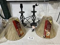 Pair of black metal lamps with twisted design and two new Portfolio brand beige lamp shades still wrapped in plastic.
