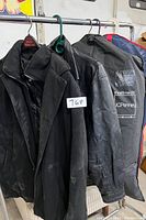 Four men's jackets hanging on hangers, including leather and wool varieties, showing the lot content