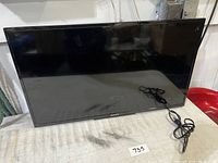 Front view of Sony KDL-32R300C TV showing screen, stand, and power cord on table.