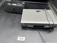 Shows both Sony VCR player and portable radio on black surface with power cords.