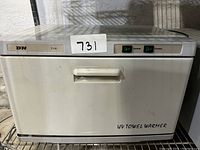 Front view of the closed UV towel warmer showing the handle and switches.