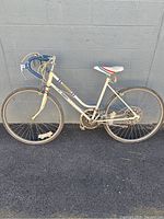Full side view of a vintage Huffy Independence bike with a white frame, blue drop handlebars, and white saddle with red and blue stripes.