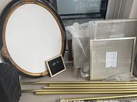 Assorted picture frames arranged side by side including a large round decorative frame and rectangular frames wrapped in bubble wrap.