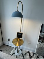 Front view of entire lamp showing curved stem, dome shade, side table and marble base