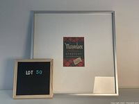 Photo of the framed advertisement poster including a lot number board.