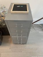 Top front view of the grey metal cabinet with 5 drawers and a small chalkboard on top.