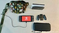 All items displayed: console booted with Joy-Con controllers attached, dock, Joy-Con grip, charger cable, carrying case and Herschel waist bag