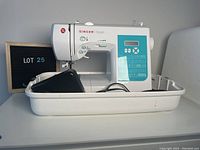 Front view of Singer Stylist 7528 sewing machine in white on plastic tray with foot pedal and cords