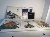 Lot of six vinyl records including Christmas and other themed albums displayed on shelf.
