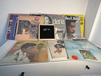 Front view of stacked vinyl records featuring New Orleans R&B, Diana Ross, Ben E. King, and James Brown with visible album art.