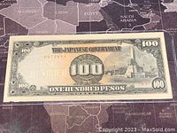 Front side of 1943 Japanese Government 100 Pesos Banknote showing denomination, building image, and serial number.