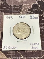 Reverse side of the 1948 Canadian 25 cent silver coin showing a caribou and denomination with handwritten notes about silver content and low mintage.