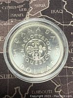 Reverse side of 1964 Canadian silver dollar featuring floral emblem and text referencing Charlottetown and Quebec meetings.