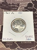 Reverse side of the 1965 Canadian 25 cents silver coin showing a caribou design and denomination details.