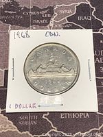Reverse side of the 1968 Canadian Silver 1 Dollar coin showing canoe with two paddlers and the date 1968.