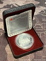 Proof silver commemorative coin in presentation case with information card.