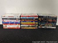 Front view of all 30 DVDs stacked showing titles on spines in two rows.