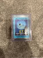 Front view of the card set in clear plastic box showing the branded cover card with E.T. and iconic bike silhouette over the moon, noting there are 87 cards in the set.