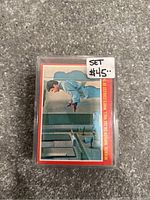 Single sealed plastic case containing the complete set of 1976 OPC Happy Days Season 2 trading cards. Car features a blue-jacketed character at a mirror on the front card.
