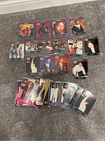 Photo showing a collection of 24 Yo Raps trading cards laid out on carpet, featuring various hip-hop artists, a mix of single and group portraits, vibrant colors and stylized designs.
