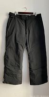 Front view of black insulated women's pants with belt loops and snap button closure