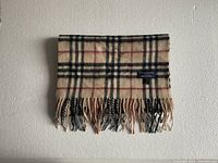 Full folded view of beige check scarf hung against wall