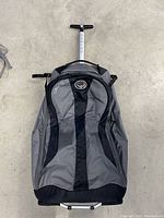 Top front view of the bag showing Osprey Ozone logo on grey-black fabric and telescoping handle pulled out.