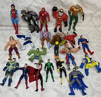 Photo showing 21 assorted superhero and cartoon character action figures arranged on white cloth.