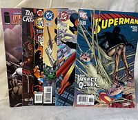 Photo shows seven comic books featuring DC Comics and Image Comics, various titles including Superman and Strangers in Paradise.