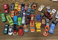 Top down view of a collection of assorted die cast toy vehicles including cars, trucks, and specialty vehicles in various colors and styles.
