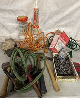 Wide view of assorted household tools including gloves, nails, clamps, hammer, nails, mallet, cords, and adhesive tube.