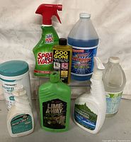 Photo showing seven household cleaning products in various containers including sprays, wipes, and gallons.