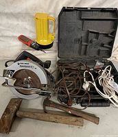 Photo showing circular saw, flashlight, screwdriver, hammers, and multiple power cords with case on white backdrop.