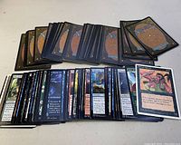 Two photos showing multiple stacks of Magic: The Gathering cards spread open to show front and back sides along a plain surface.