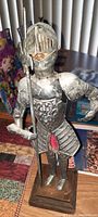Front view of the 10-inch tin suit of armor statue showing detailed embossed armor, spear held in right hand, and face visible under visor.