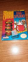 Front of sealed game box showing Short Order and Egg-Splode titles with Power Pad included