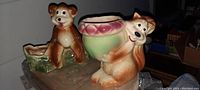 Two vintage 6-inch animal figural planters: brown monkey and dog holding a planter bowl, displayed on books.