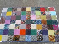 Full view of quilt laid flat, showing patchwork squares in various colors and patterns.