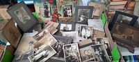 Wide view of the assortment of early cabinet photographs spread on a table, showing various mounted photos including a girl in a bathing suit